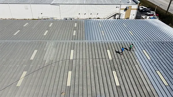 A team cleaning and maintaining a large metal ranch roof to ensure durability and functionality.