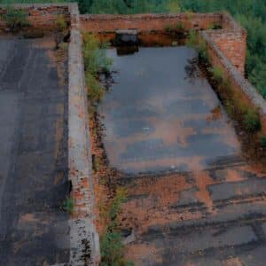 A flat commercial roof with water pooling and signs of weather-related wear and tear.