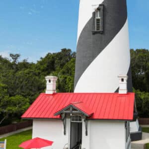 A lighthouse with a bright red roof, demonstrating all kinds of commercial properties can opt for effective energy-saving roofing options.