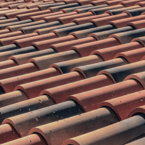 a close-up of a sun-exposed terracotta tile roof showing signs of discoloration and fading, illustrating the impact of UV exposure and the importance of regular inspections to prevent material degradation.