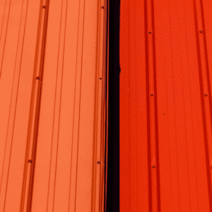 a close-up of a metal roof with visible loose fasteners and two sheets coming apart, highlighting the potential for panel misalignment and leaks if not properly secured.