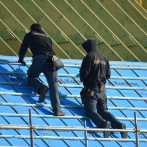 two roofing professionals working on a metal roof installation, highlighting labor costs and materials involved in metal roof repairs.