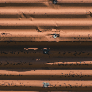 close-up of a worn corrugated metal roof panel with visible rust and fastener holes, highlighting the hidden damage that can lead to costly repairs.