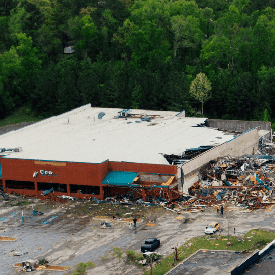 a large commercial building with severe roof collapse and structural damage following a disaster, highlighting the impact of storm-related events and the importance of navigating insurance claims