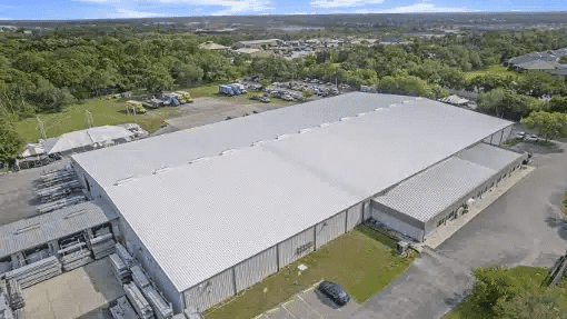 aerial view of a large commercial warehouse with a clean, light-coloured flat metal roof, representing Troyer Commercial Roofing’s completed project for U.S. Tent Rental