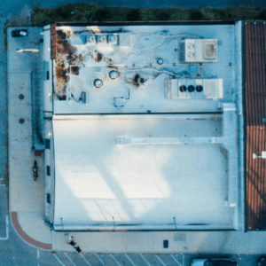 aerial view of a flat commercial roof showing water damage, staining, and equipment surrounded by ponding areas