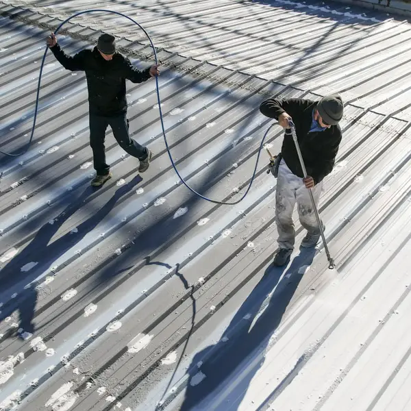 Metal roof restoration team spraying roof