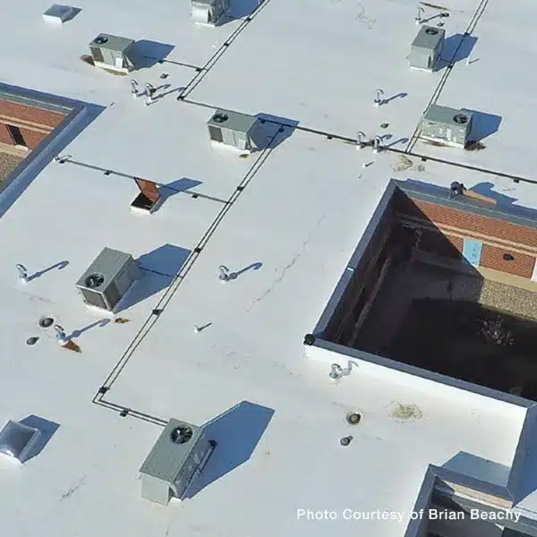 An aerial view of a white commercial flat roof featuring multiple HVAC units