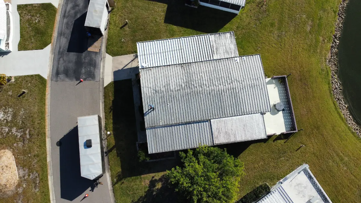 Commercial metal roof being restored with protective coating, showing the importance of proper installation and materials for a valid roofing warranty in Florida.