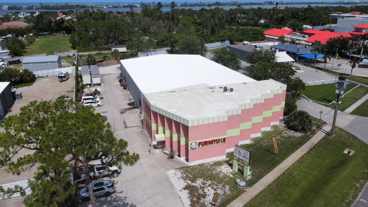 A commercial furniture store in Florida with a newly applied bright white reflective roof coating, shown from an aerial view to highlight energy-efficient roof performance.
