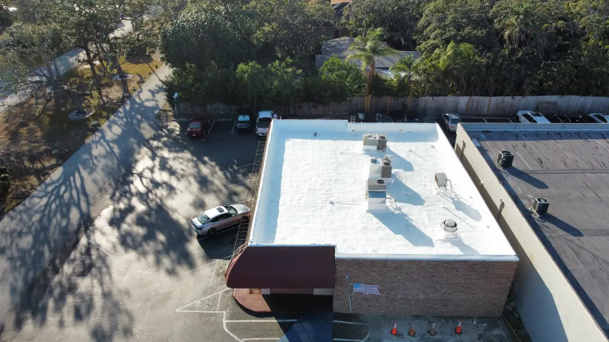 modified-bitumen-roof-restoration-florida-commercial-building Aerial view of a Florida commercial building with a restored modified bitumen roof coated in a reflective white roof system