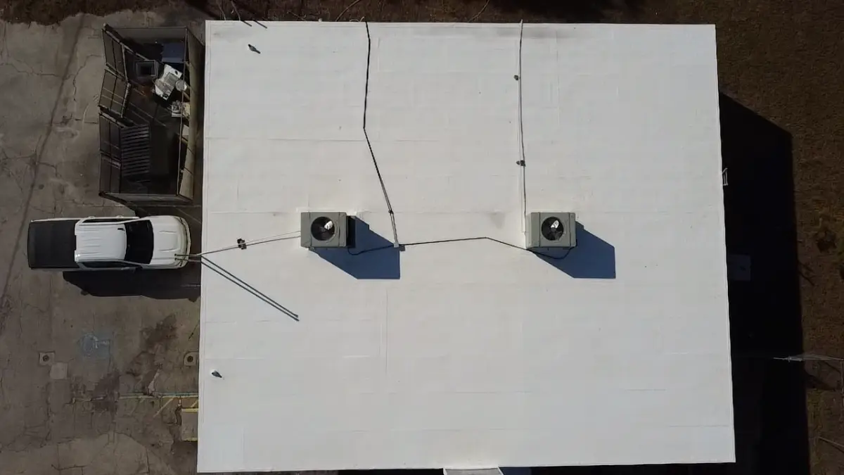 modified-bitumen-roof-maintenance-florida-commercial-building Aerial view of a white commercial flat modified bitumen roof in Florida with a reflective coating and rooftop HVAC units
