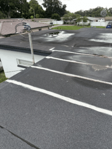 Standing water at a clogged roof drain on a commercial flat roof caused by cutting corners on drainage details